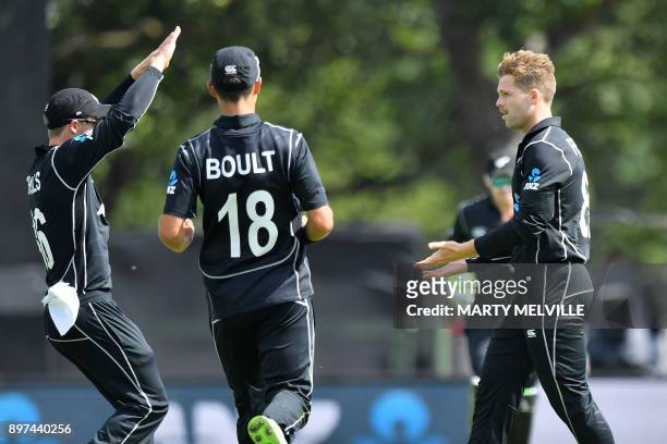 New Zealand's Lockie Ferguson celebrates with teammates Henry Nicholls and Trent Boult after dismissing West Indies batsman Jason Mohammed during the...