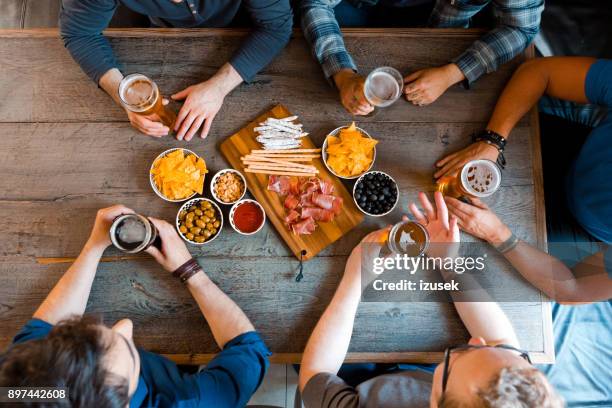 vista superior de amigos sentados sobre cerveza en la mesa en pub - artisanal food and drink fotografías e imágenes de stock