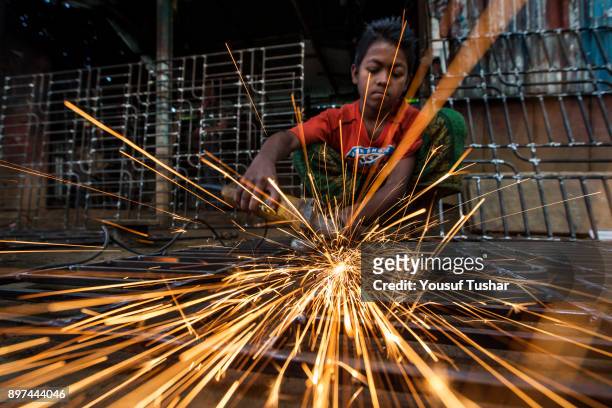 Boy working with a grinding machine in a local workshop at Gazipur.