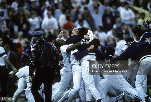 Infielder Al Newman Frank Viola and a teammate of the Minnesota Twins with the rest of the team behind celebrates with jubilation after the Twins...
