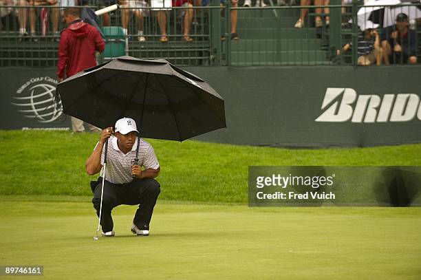 Bridgestone Invitational: Tiger Woods holding umbrella while lining up putt during Saturday play at Firestone CC. Rain, weather. Akron, OH 8/8/2009...