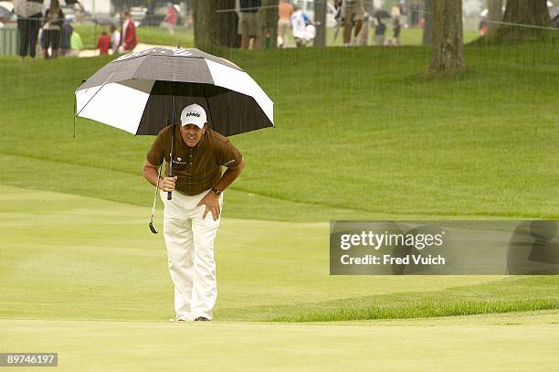 Bridgestone Invitational: Phil Mickelson holding umbrella before missing birdie putt on No 14 during Saturday play at Firestone CC. Rain, weather....