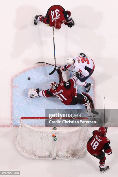 Goaltender Scott Wedgewood of the Arizona Coyotes dives to cover the puck as Alex Chiasson of the Washington Capitals and Zac Rinaldo skate in during...