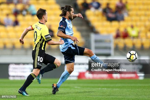 Joshua Brillante of Sydney FC passes under pressure from Michael McGlinchey of the Phoenix during the round 12 A-League match between the Wellington...