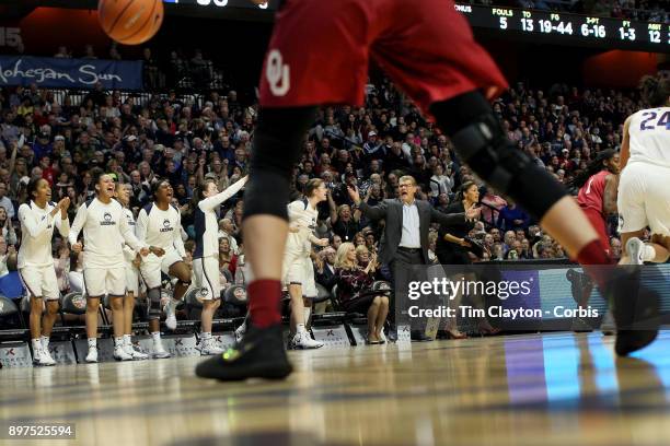 Head coach Geno Auriemma of the UConn Huskies on the sideline while recording his 1000th win as head coach of the team as the Uconn team celebrate a...