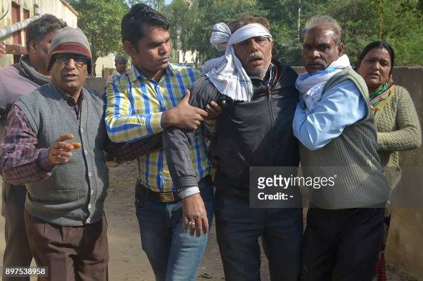 Indian men escort an injured bus passenger after an accident in Sawai Madhopur, some 160 kilometres from Jaipur in Rajasthan state, on December 23,...