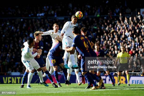 Raphael Varane of Real Madrid jumps to wina header during the La Liga match between Real Madrid and Barcelona at Estadio Santiago Bernabeu on...