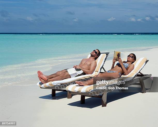 couple sunbathing - sdraio da spiaggia foto e immagini stock