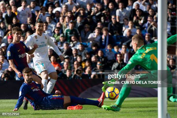 Barcelona's German goalkeeper Marc-Andre Ter Stegen stops the ball in front of Real Madrid's Portuguese forward Cristiano Ronaldo and Barcelona's...