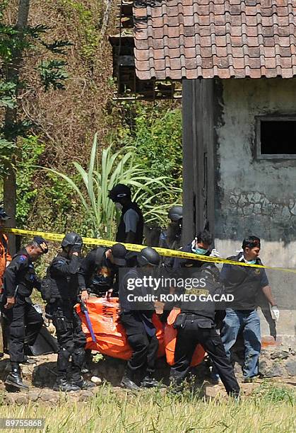 This photo taken on August 8, 2009 shows Indonesian anti-terror police commandos carrying a body bag out of a farm house in Beji village in Central...