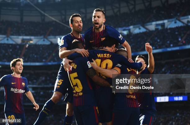 Lionel Messi of Barcelona celebrates after scoring his sides second goal with his team mates during the La Liga match between Real Madrid and...