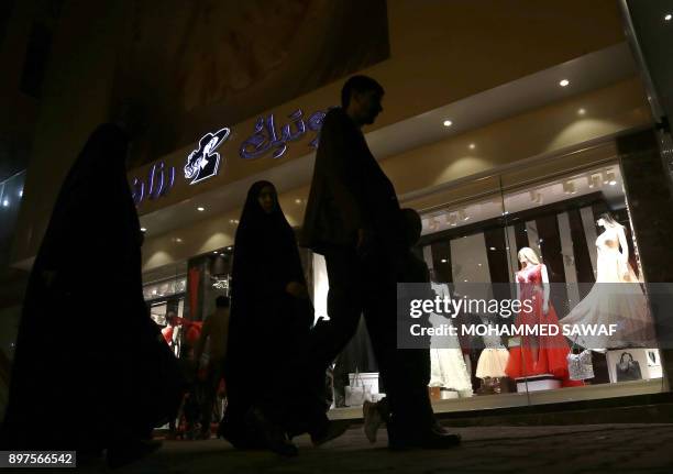Iraqis walk past a window display of a shop selling women's clothes in the Shiite holy city of Karbala on December 22, 2017. Activists in Iraq's...