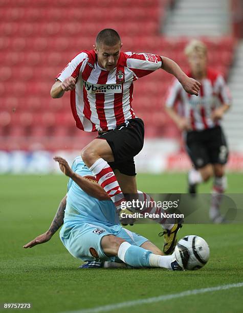 Adam Lallana of Southampton jumps over the challenge from Ramone Rose of Northampton Town during the Carling Cup Round One Match between Southampton...