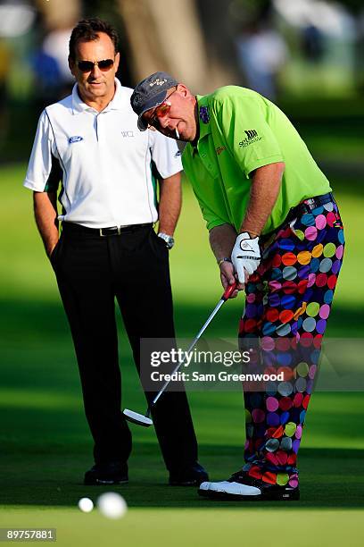 John Daly putts while coach Rick Smith looks on during the third preview day of the 91st PGA Championship at Hazeltine National Golf Club on August...