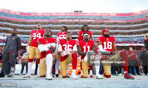 Eli Harold, Eric Reid, Marquise Goodwin and Louis Murphy of the San Francisco 49ers kneel on the sideline during the anthem as Solomon Thomas, Reuben...