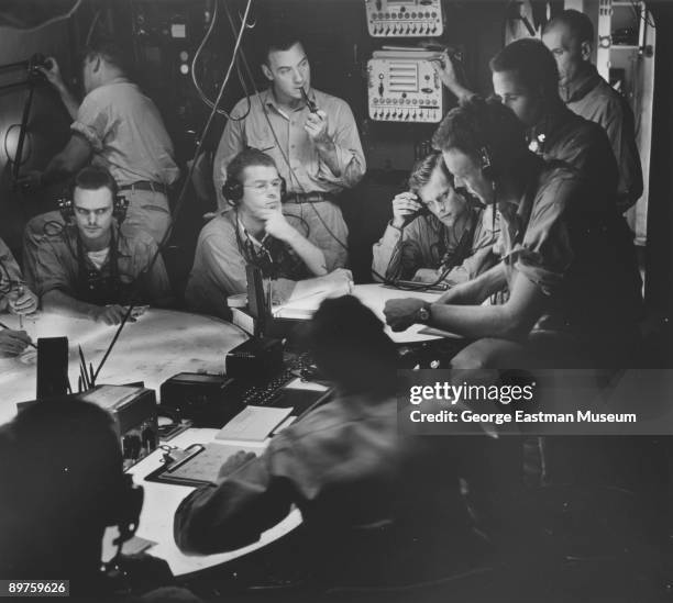 Group of soldiers gathered together in the Air Plot room of the aircraft carrier U.S.S. Lexington, during World War 2, November 1943.