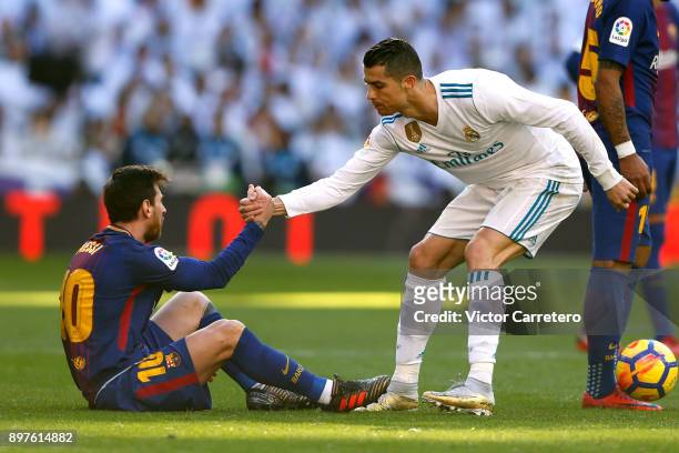 Cristiano Ronaldo of Real Madrid helps Lionel Messi of Barcelona during the La Liga match between Real Madrid and Barcelona at Estadio Santiago...