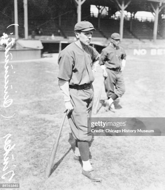 Informal full-length portrait of Hall of Fame baseball player Joe Tinker of the National League's Cincinnati Red, leaning on a baseball bat, standing...