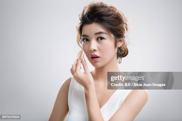 young woman applying facial powder - powder puff stock pictures, royalty-free photos & images