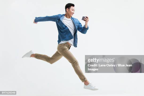 young man jumping with a smart phone - phone side view stock pictures, royalty-free photos & images