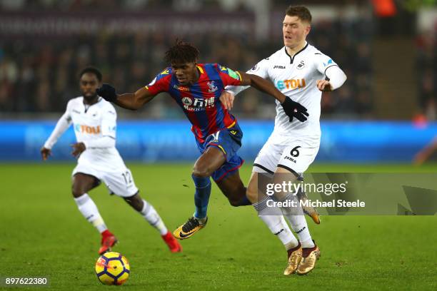 Wilfried Zaha of Crystal Palace escapes a challenge from Alfie Mawson of Swansea City during the Premier League match between Swansea City and...