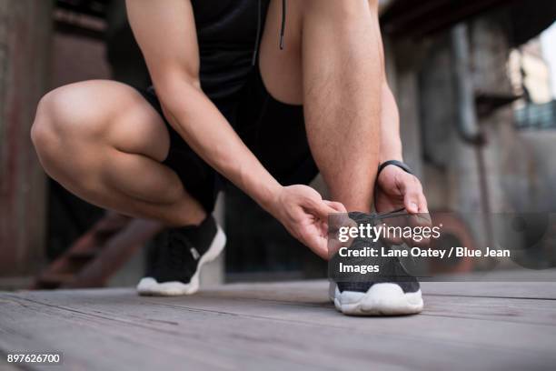 young man tying shoe lace - lace fastener stock-fotos und bilder