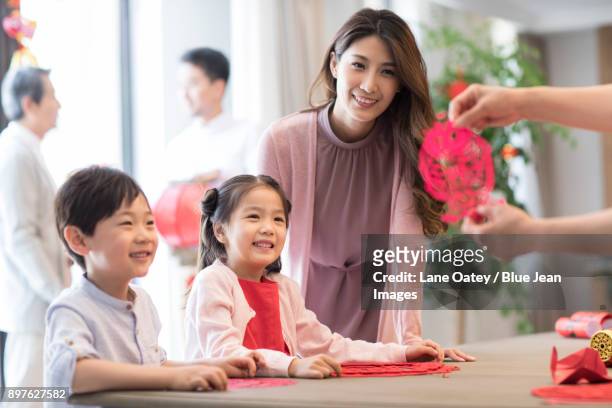 grandchildren and grandmother with chinese new year paper-cut - mom blessing son stockfoto's en -beelden