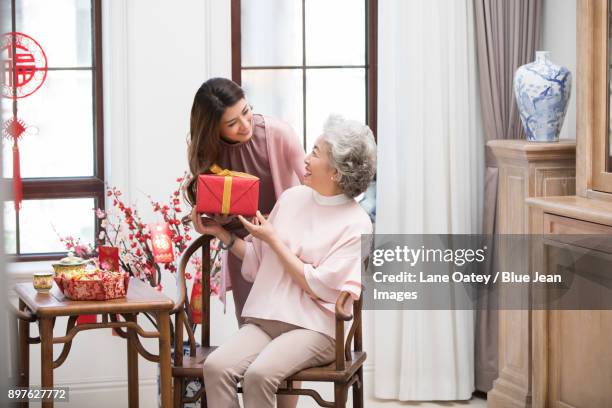 daughter giving gift to her mother during chinese new year - bainian stock pictures, royalty-free photos & images