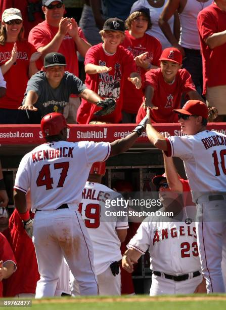Howie Kendrick of the Los Angeles Angels of Anaheim is greeted by coach Ron Roenicke and Angels fans as he returns to the dugout after hitting a...