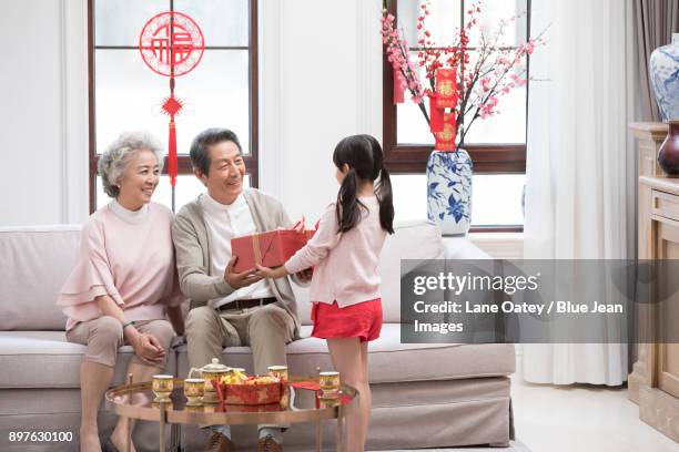 granddaughter giving gift to grandparents during chinese new year - lunar new year cup 2017 stock-fotos und bilder