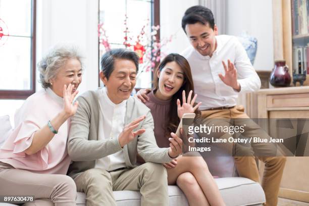 happy family having video chat on smart phone during chinese new year - bainian stock pictures, royalty-free photos & images