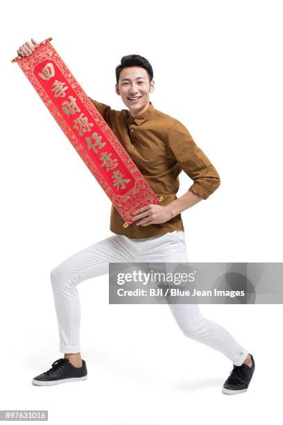 cheerful young man with couplet celebrating chinese new year - bainian stock pictures, royalty-free photos & images