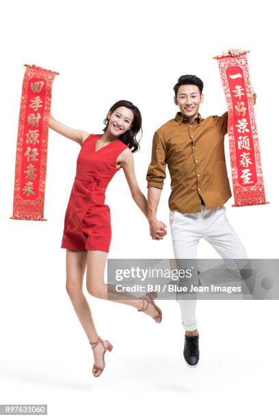 cheerful young couple with couplets celebrating chinese new year - bainian stock pictures, royalty-free photos & images