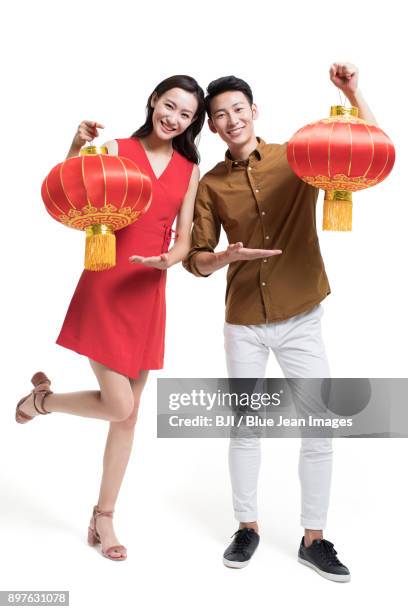 cheerful young couple celebrating chinese new year with traditional lanterns - bainian stock pictures, royalty-free photos & images