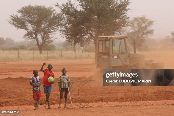 Nigerien children walk and play along the fences of the Barkhane French air force base on December 23 in Niamey. / AFP PHOTO / ludovic MARIN