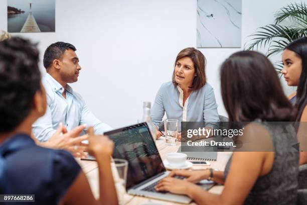 manager talking to her employees in the office at the formal meeting - hierarquia de corporação imagens e fotografias de stock