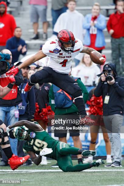 Justin Stockton of the Texas Tech Red Raiders leaps over Ronnie Hoggins of the South Florida Bulls in the first half of the Birmingham Bowl at Legion...