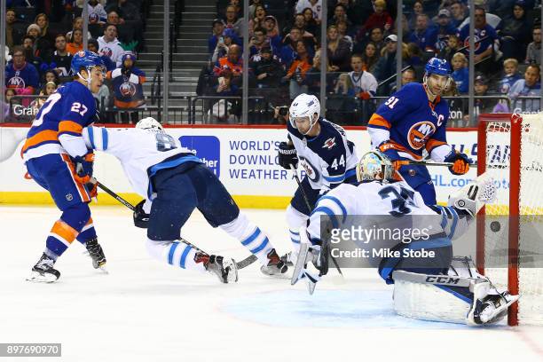 Anders Lee of the New York Islanders shoots the puck past Steve Mason of the Winnipeg Jets for a first period goal at Barclays Center on December 23,...