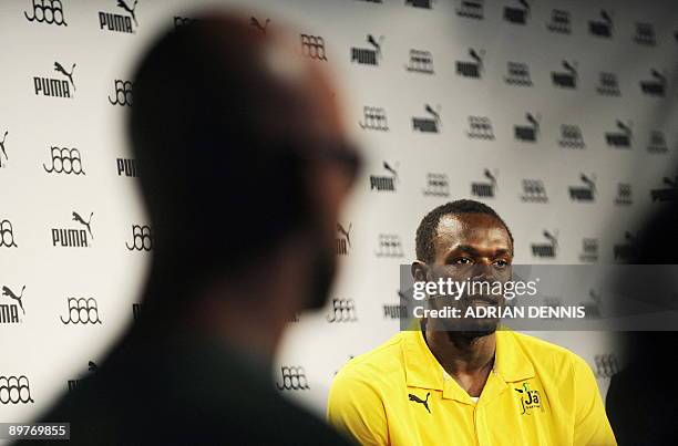 Double-Olympic sprint champion Usain Bolt of Jamaica is flanked by a security guard while holding a press conference in Berlin August 13, 2009 were...