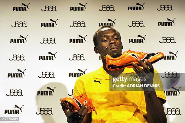 Double-Olympic sprint champion Usain Bolt of Jamaica admires his new running spikes while holding a press conference in Berlin August 13, 2009....
