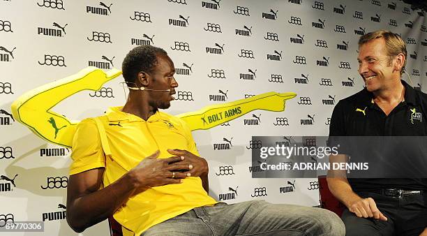 Olympic sprint champion Usain Bolt of Jamaica wearing "Bolt Arms" looks over towards Jochen Zeitz, Chairman and CEO of Puma during a press conference...