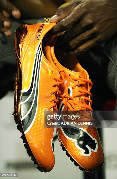 Double-Olympic sprint champion Usain Bolt of Jamaica holds a new set of running spikes after being presented with them during a press conference with...