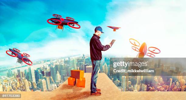 delivery person sends off drones with packages from skyscraper in future city - drone parcel stock pictures, royalty-free photos & images