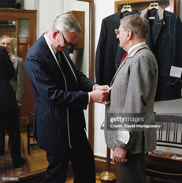 Head cutter Dennis Hallbery measures a customer at Anderson & Sheppard Ltd., a tailor shop on London's Savile Row, circa 1990.