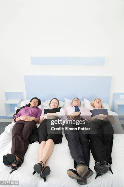 four business people lying in a bed - overdoing stock pictures, royalty-free photos & images