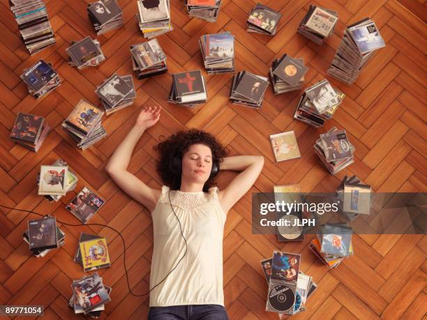 woman lying on floor, listening to music - compact disc fotografías e imágenes de stock