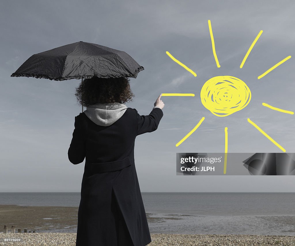 Woman painting sun onto grey sky