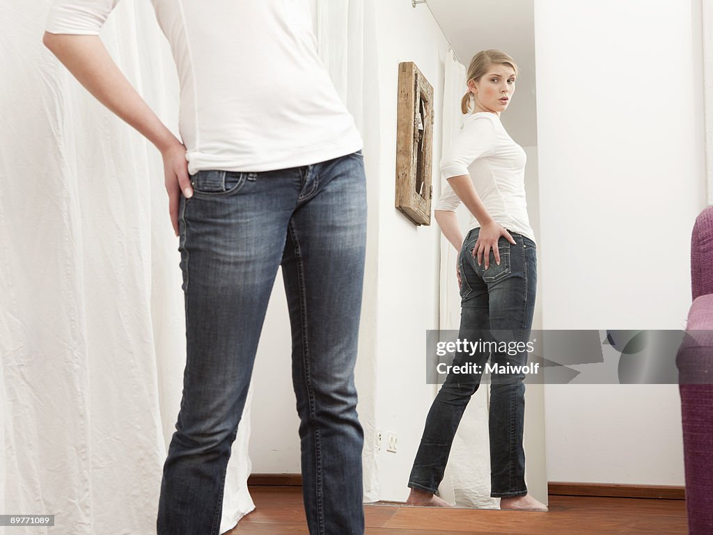 Woman checking her body in the mirror.