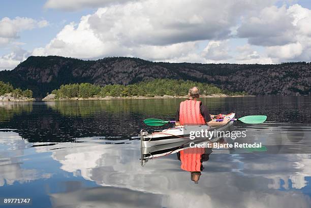 man kayaking on calm lake - bjarte rettedal stock pictures, royalty-free photos & images