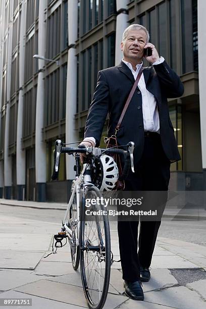 businessman pushing bicycle - bjarte rettedal stock-fotos und bilder